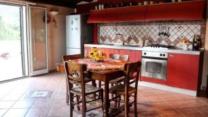 a kitchen with red cabinets and a table and chairs at Villa Plaia in Castellammare del Golfo