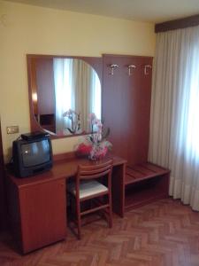 Habitación con escritorio, TV y espejo. en Hotel Monte Fior, en Foza