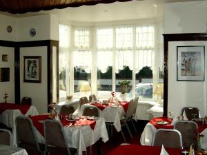 Braedene Lodge في بينتون: غرفة طعام مع طاولات قماش الطاولة الحمراء والبيضاء