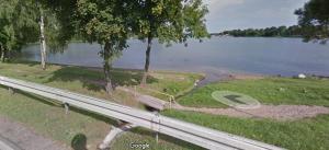 a park bench next to a lake and a road at Pokoje gościnne Venezia in Czaplinek