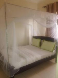 Una cama con dos almohadas verdes encima. en Coffee Tourist Motel, en Kampala