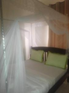 1 cama con 2 almohadas verdes y dosel en Coffee Tourist Motel, en Kampala