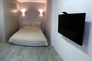 ein kleines Schlafzimmer mit einem Bett und einem Flachbild-TV in der Unterkunft Люстдорфская дорога , квартира-студия in Odessa