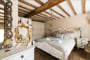 ein Schlafzimmer mit einem weißen Bett und einem Spiegel in der Unterkunft Tudor Cottage in Fairford