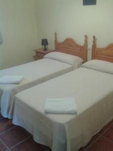 2 camas en una habitación con sábanas blancas en Casa Detrés en Cogollos de Guadix