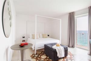 a white bedroom with a white canopy bed and a table at Dimora Talenti in Polignano a Mare