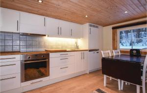 a kitchen with white cabinets and a table and a stove at Beautiful Home In Ambjörby With Sauna in Ambjörby