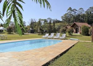 a swimming pool with lounge chairs next to a house at Pousada dos Girassóis in Cunha
