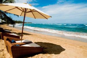a beach with two chairs and an umbrella on the sand at Villa Montaña Beach Resort in Isabela +24 photos