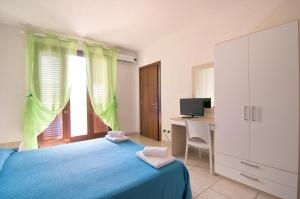 a bedroom with a blue bed and a desk and a window at Giardino Dei Suoni B&B in Melendugno