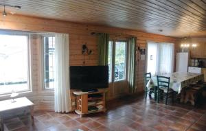 ein Wohnzimmer mit einem Flachbild-TV und einem Tisch in der Unterkunft Gorgeous Home In Lindesnes With House Sea View in Jåsund