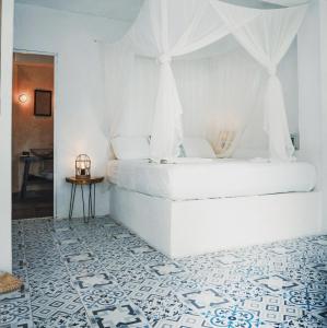 a white bedroom with a bed with a canopy at Casa del Pavo Real Boutique Hostel in Palomino