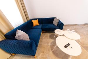 a blue couch in a living room with two tables at Santa Oliva Suites in Ksamil