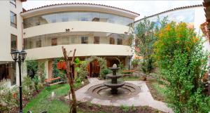 a building with a fountain in front of it at Taypikala Hotel Cusco in Cusco