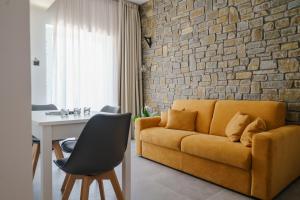 sala de estar con sofá amarillo y pared de ladrillo en Cilento Victory House, en Serramezzana