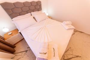 a bedroom with a white bed with towels on it at Santa Oliva Suites in Ksamil