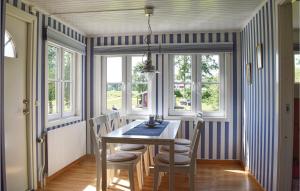 a dining room with a table and chairs and windows at Amazing Home In Bolmsö With Lake View in Bolmstad