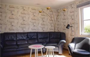 a living room with a black leather couch and two tables at Amazing Home In Bolmsö With Lake View in Bolmstad