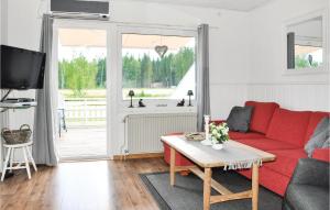 ein Wohnzimmer mit einem roten Sofa und einem Tisch in der Unterkunft Cozy Home In motsfors With Kitchen in Gryttved