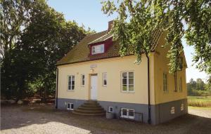 a small yellow and white house with a tree at Holiday Home Tomelilla 03 in Bollerup