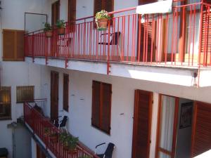 un edificio con balconi rossi, sedie e piante di Albergo Luca a Ivrea