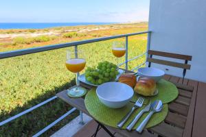 una mesa con 2 copas de vino y comida en el balcón en Santa Cruz Ocean View Villa, en Bombardeira