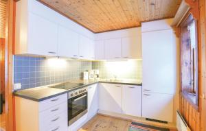 a kitchen with white cabinets and a wooden ceiling at 2 Bedroom Stunning Home In Sysslebck in Sysslebäck