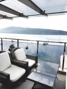 patio z 2 krzesłami, stołem i wodą w obiekcie Apartments Admiral w mieście Herceg Novi