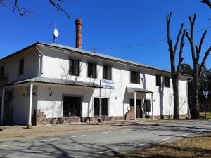 an old white building sitting on the side of a street at White House puhkemaja in Uulu
