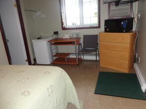 Schlafzimmer mit einem Bett, einer Kommode und einem Schreibtisch in der Unterkunft Happy Motel in Edmundston