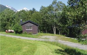 duas pessoas sentadas num banco em frente a um barracão em Cozy Home In Isfjorden With House A Panoramic View em Tokle