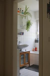 a bathroom with a sink and a white tiled wall at Bed & Breakfast Bonn in Bonn