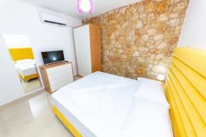 a bedroom with a bed and a stone wall at Santa Oliva Suites in Ksamil
