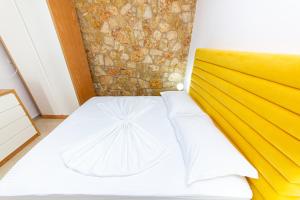 a small bedroom with a white bed with a yellow headboard at Santa Oliva Suites in Ksamil