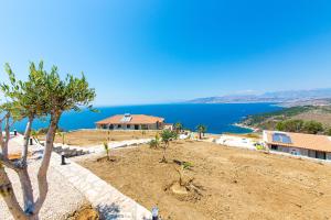 a house on top of a hill next to the ocean at Santa Oliva Suites in Ksamil