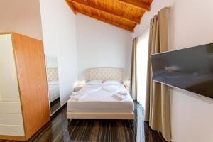 a bedroom with a bed and a flat screen tv at Santa Oliva Suites in Ksamil