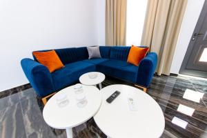 a living room with a blue couch and two tables at Santa Oliva Suites in Ksamil