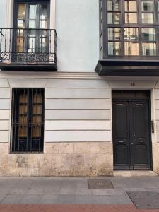 un edificio con due porte nere e due finestre di Apartamento Juan de Herrera VUT47168 a Valladolid