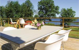 a table with white chairs and a vase of flowers on a deck at Amazing Home In Bolmsö in Bolmsö