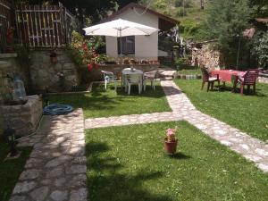 a patio with a table and an umbrella in a yard at Vila MAGDA in Mavrovo