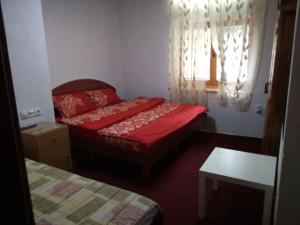 a small bedroom with a red bed and a window at Vila MAGDA in Mavrovo