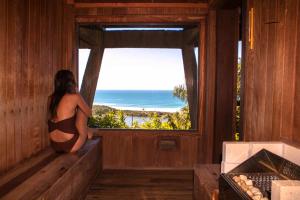 a woman in a bathing suit looking out of a window at Solar Mirador Exclusive Resort e SPA in Praia do Rosa