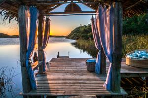 a wooden dock with a bridge over a body of water at Solar Mirador Exclusive Resort e SPA in Praia do Rosa