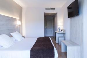 リョレート・デ・マルにあるHotel Helios Lloretのベッドとテレビが備わるホテルルームです。