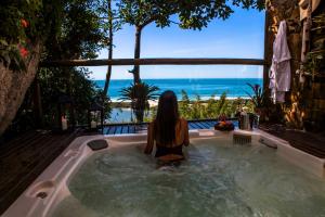 a woman sitting in a hot tub looking out at the ocean at Solar Mirador Exclusive Resort e SPA in Praia do Rosa