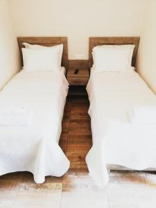 2 bedden in een kamer met witte lakens bij Sunset in Plataria