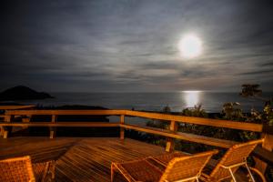 a deck with two chairs and the moon over the ocean at Solar Mirador Exclusive Resort e SPA in Praia do Rosa