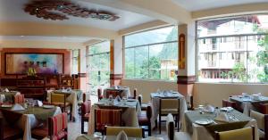 un restaurante con mesas y sillas en una habitación con ventanas en Hotel Taypikala Machupicchu, en Machu Picchu