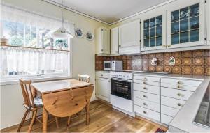 a kitchen with white cabinets and a wooden table at 5 Bedroom Lovely Home In Seim in Seim