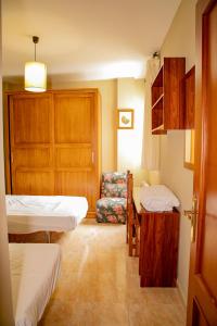 a small room with two beds and a chair at Apartamentos Rurales Labrador in Arbuniel